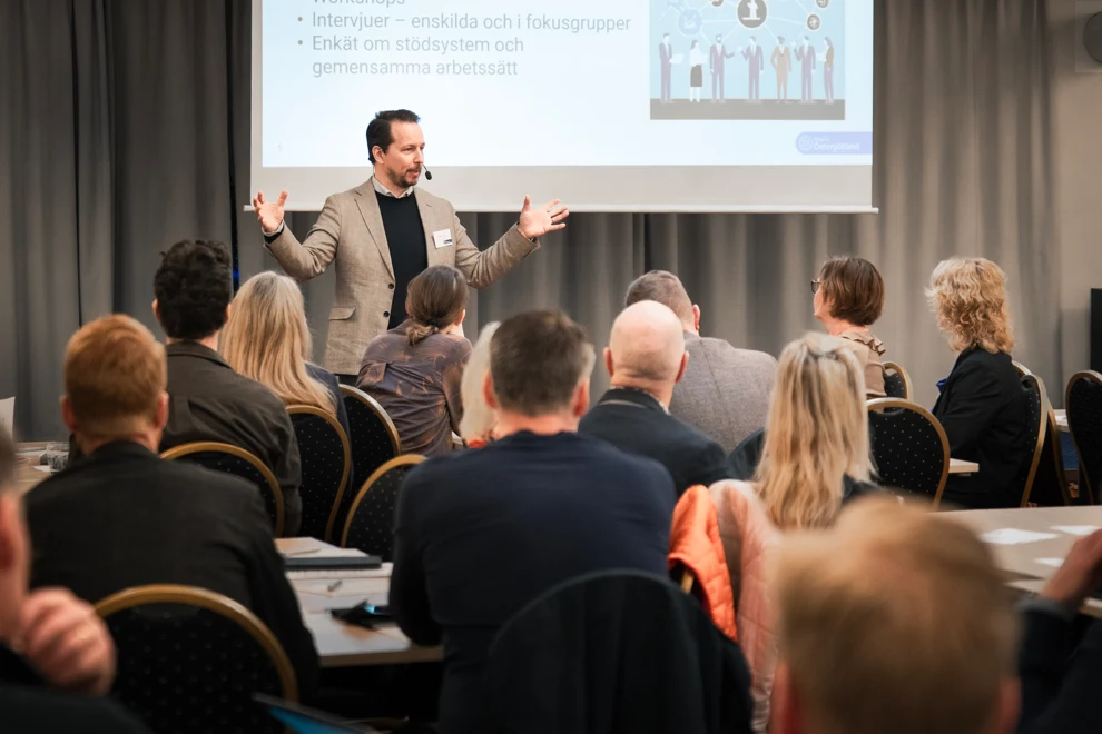 En man som håller ett föredrag inför en grupp människor.