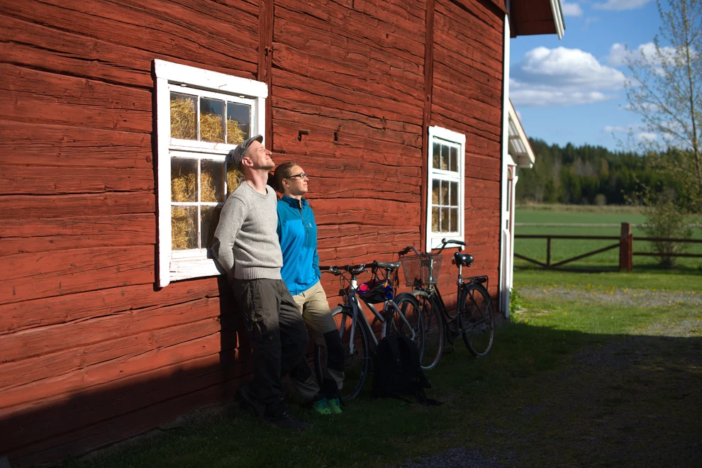 Två personer som står bredvid en röd ladugård.