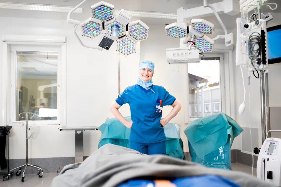 En operationssjuksköterska i blå kläder och mössa. Kvinnan ler mot kameran.