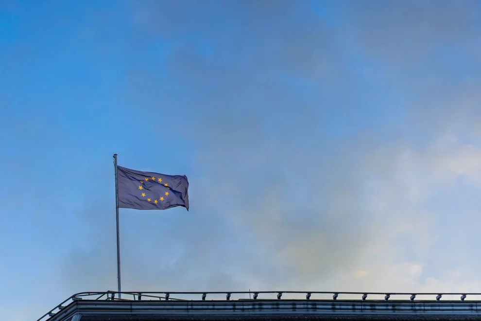 En europeisk flagga som vajar på taket av en byggnad.