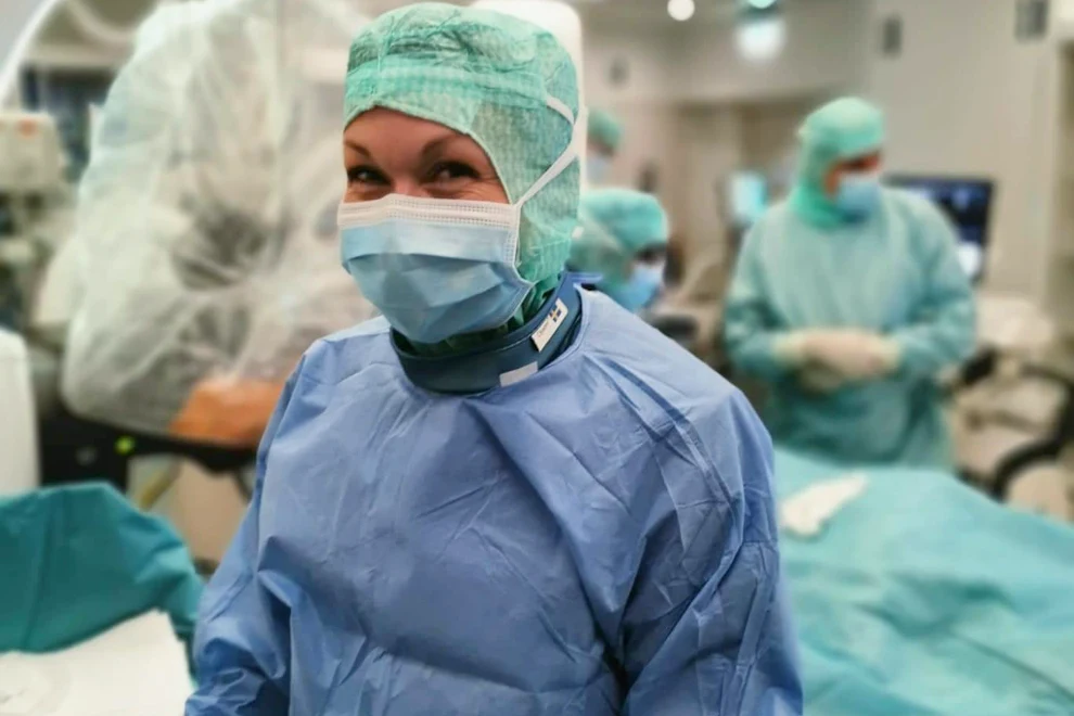 En kvinna i blå operationsrock och munskydd.