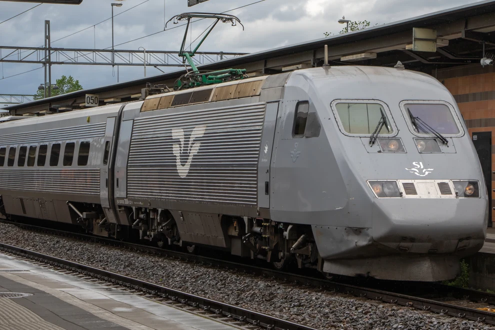 Ett silverfärgat tåg som rullar in på en järnvägsstation.