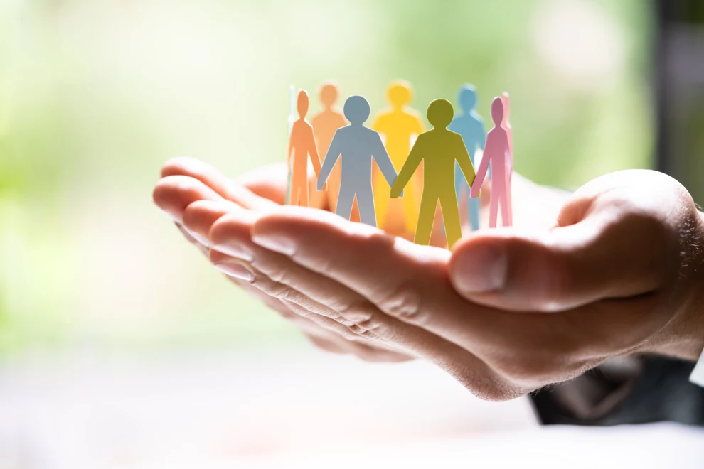En person som håller i en liten grupp pappersfigurer.